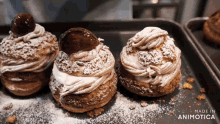 three pastries with powdered sugar on top are on a tray made by animatica