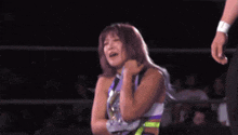 a woman is standing in a wrestling ring with a man in the background .