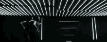 a group of people are standing in a dark room with a lot of lights on the ceiling .