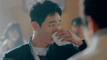 a man is drinking a cup of coffee from a white cup .