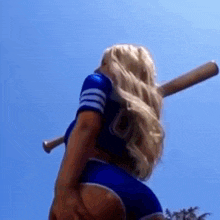 a woman in a baseball uniform is holding a baseball bat over her shoulder .