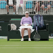 a tennis player sits on a couch with a babolat bag