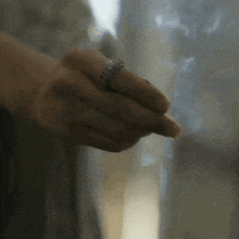 a close up of a person 's hand with a ring on their finger .