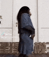 a monkey wearing a blue dress is dancing in front of a wall with chinese letters on it
