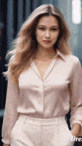 a woman wearing a pink shirt and white pants is standing with her hands in her pockets