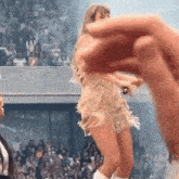 taylor swift is dancing on stage in front of a crowd while holding a microphone .