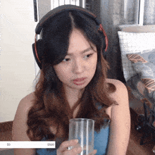 a woman wearing headphones is holding a glass with a $ 500 sticker on the bottom right