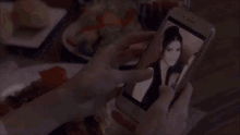 a person is taking a picture of a woman with a cell phone .