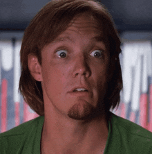 a man with long hair and a beard is wearing a green shirt