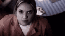 a woman in a jail cell is looking at the camera with a sad look on her face .