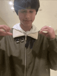 a young man wearing a jacket with a white hood and buckled collar