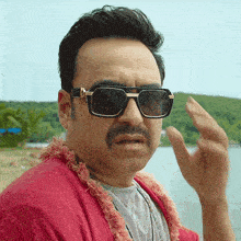 a man with a mustache wearing sunglasses and a red sweater