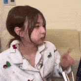 a young girl is sitting on a couch with chopsticks in her hand and making a funny face .