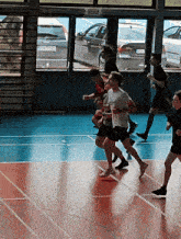 a group of people running in a gym with a sign that says ' asics '
