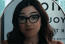 a woman wearing glasses is standing in front of a sign that says enjoy