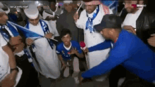 a man in a blue shirt is kneeling down in front of a crowd