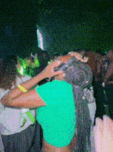 a woman in a green shirt is standing in a crowd at a party