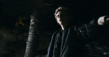 a man in a black jacket is standing in the dark with his arms outstretched