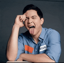 a man wearing a blue shirt with msgm on it sticking out his tongue