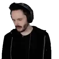 a man with a beard wearing headphones and a black jacket is making a funny face .