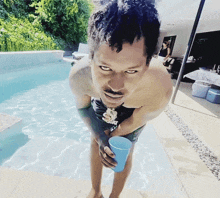 a shirtless man is standing in a pool holding a cup