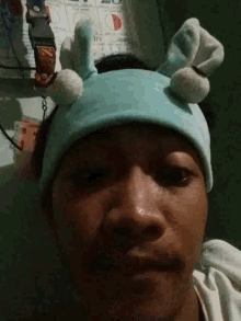 a close up of a person wearing a blue hat with white pom poms