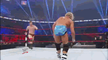 two men are wrestling in a ring and one of them is wearing a blue shorts