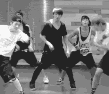 a black and white photo of a group of young men dancing in a room .