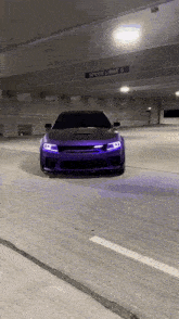 a purple car is driving in a parking garage under a speed limit sign