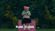 a man in a pink hat is sitting on a pink box with the words flak flakk written above him
