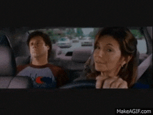 a woman is driving a car next to a man in a shirt that says champion