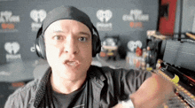 a man wearing headphones stands in front of a wall that says iheartradio