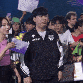 a man wearing a jacket that says gd stands in a crowd