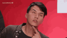 a young man is making a funny face with his finger on his chin