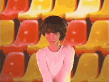 a woman in a white shirt is standing in front of a row of yellow and red seats .