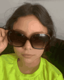 a girl wearing a neon yellow shirt and sunglasses