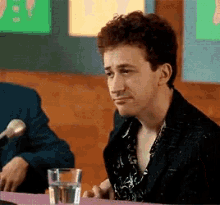 a man is sitting at a table with a glass of water