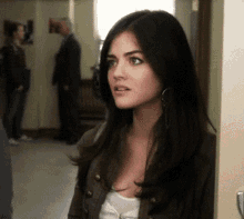 a woman with long dark hair is standing in a hallway looking at the camera