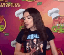 a woman in a black shirt is standing in front of a pink background with chefs hats .