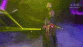 a wrestler is standing on a stage in front of a purple and yellow light show .