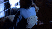 a person in a blue shirt is laying down in a dark room .