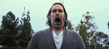 a man with a beard and long hair is screaming with his mouth open