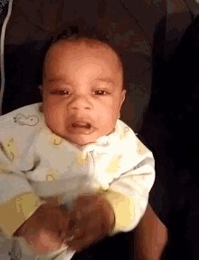 a baby is being held in someone 's arms and making a face