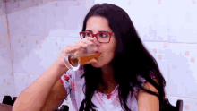 a woman with glasses is drinking a glass of beer