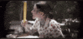 a woman is sitting at a table holding a pencil in her hand .