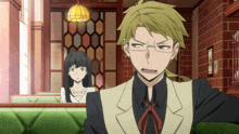 a man and a woman are sitting in a room with a brick wall