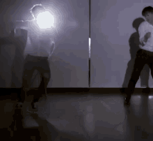 a man in a white shirt is dancing in front of a wall