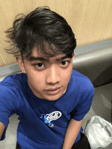 a young man wearing a blue shirt with a drawing of a person on it