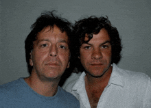 two men are standing next to each other and one has a white shirt on