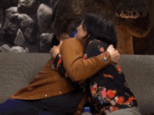 a man and woman are hugging and kissing on a couch in front of a bear